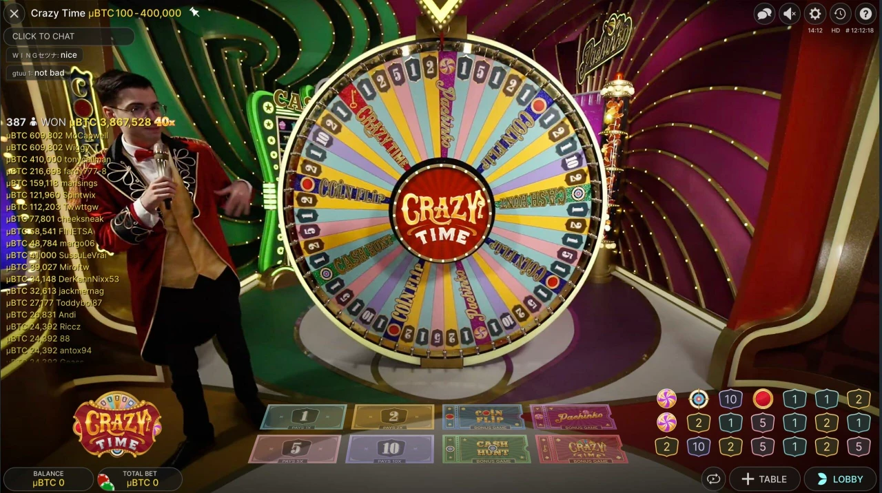 Programleder som gestikulerer mot et stort fargerikt spinnehjul i et "crazy time" casinospill på nett game show-setting.